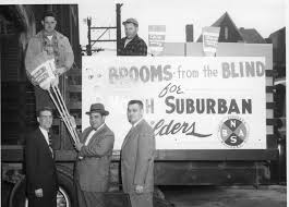 An antique photo showing men with a truck selling "brooms from the blind" according to the sign