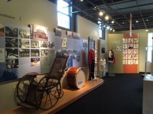 Image of various exhibits at Museum including wheelchair, drum, band uniform and institution photos.