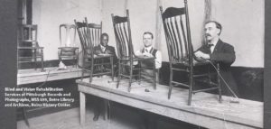 Old black and white photo of men who are blind caning chairs at a long table.