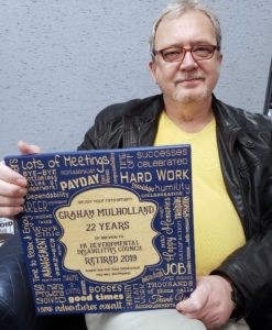 Photo of Graham Mulholland holding a retirement plaque for 22 years service.