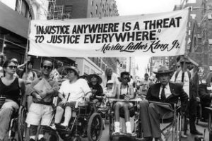 A crowd holding up a banner that says "Injustice anywhere is a treat to justice everywhere" by MLK