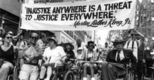 A crowd holding up a banner that says "Injustice anywhere is a treat to justice everywhere" by MLK