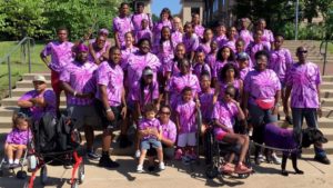 A group of black people wearing matching purple shirts at a fundraising event