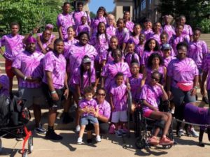 A group of black people wearing matching purple shirts at a fundraising event