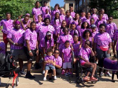 A group of black people at a disability fundraising event wearing matching purple shirts
