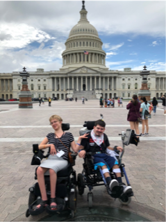 Two people using wheelchairs sitting in the courtyard to the US Capitol Building