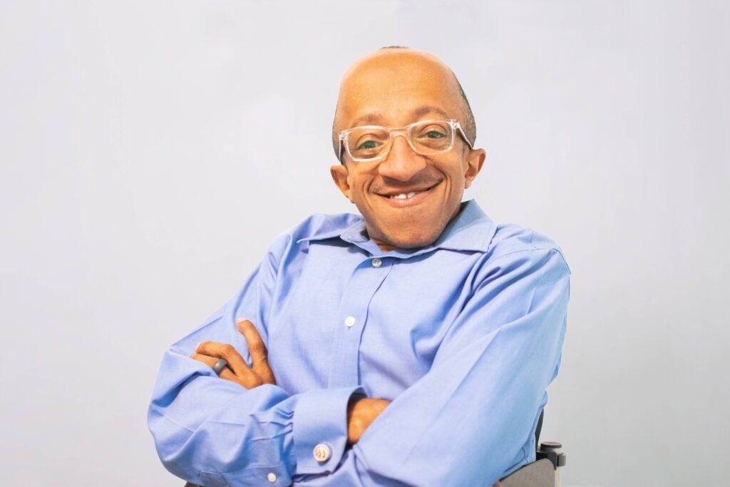 Chaz Kellem, a smiling Black man wearing eyeglasses and a blue button down shirt