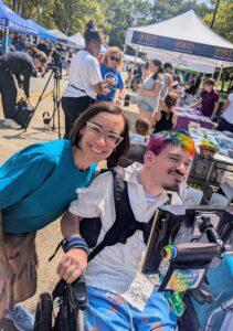 Two people, one using a wheelchair, at our table at Disability Pride