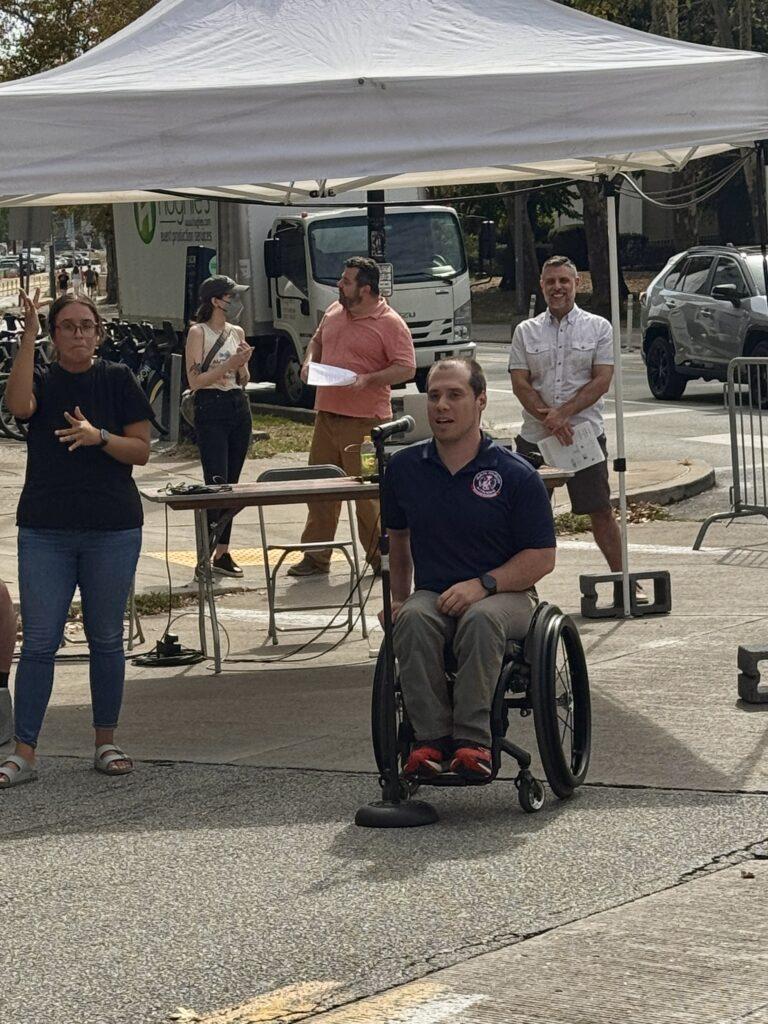 A man using a wheelchair speaking at the event.