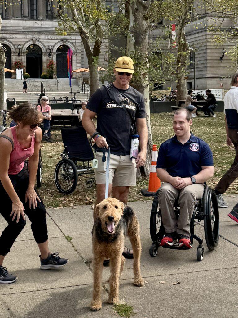 Several people admire a dog on a leash.