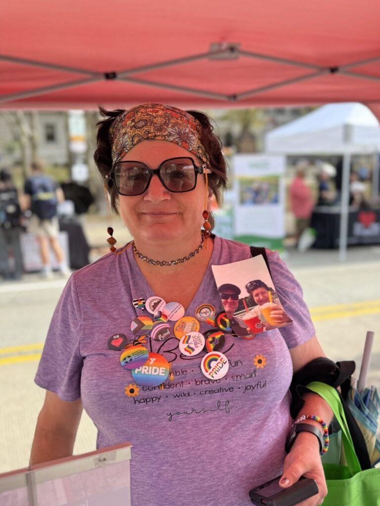 A woman in a purple shirt with lots of pride buttons attached to the front of it.