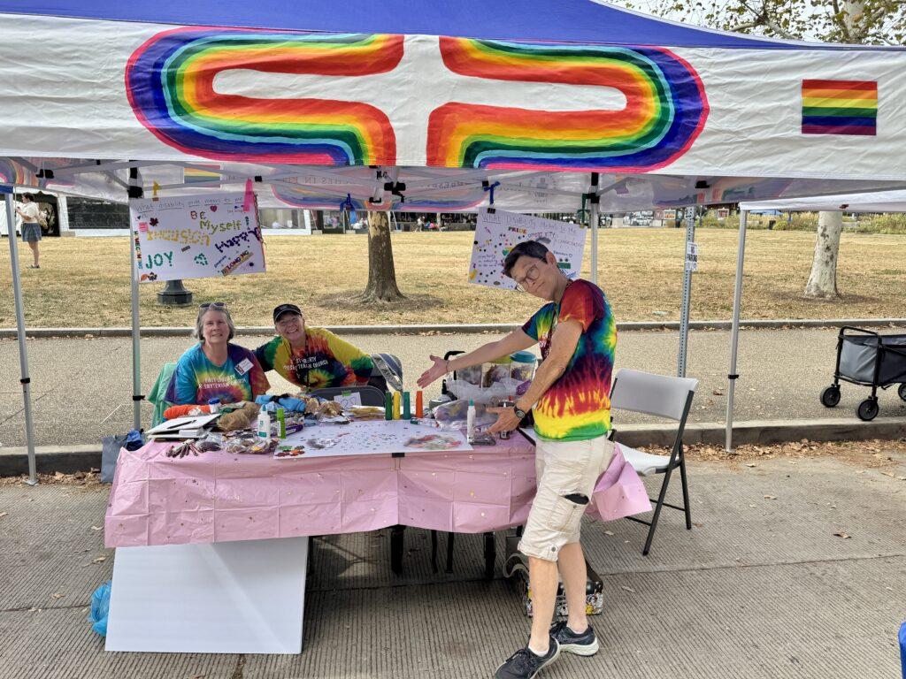 East Liberty Presbyterian Church's booth with three people smiling and posing for a photo.