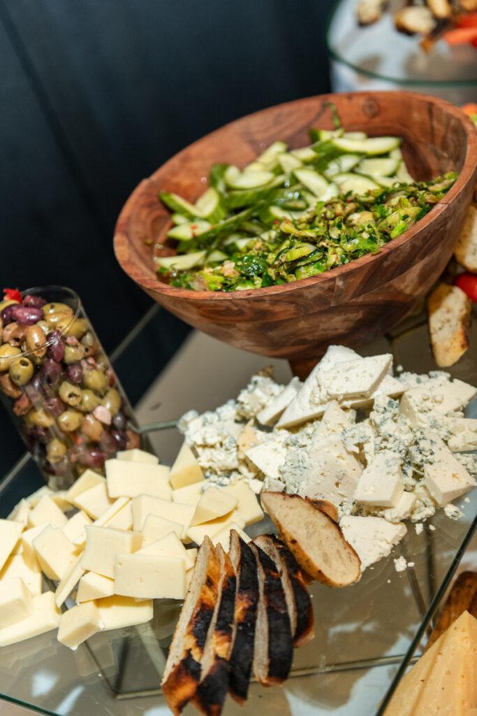 A food spread of cheese, veggies, olives.