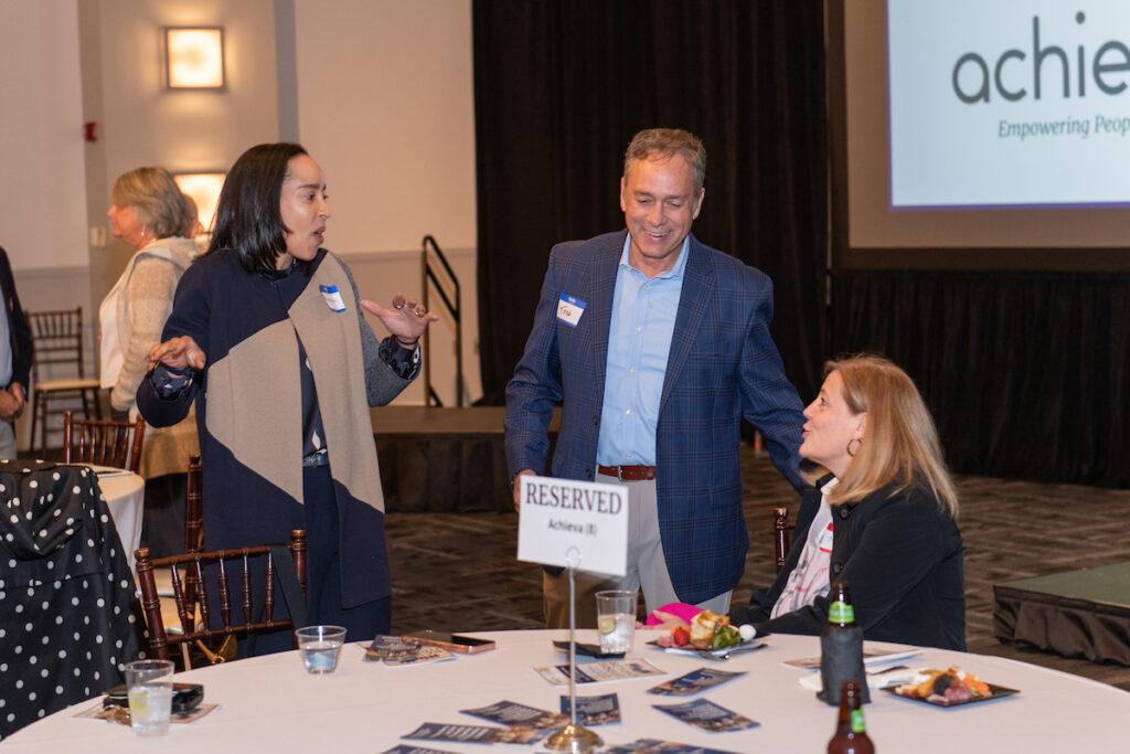 Two women and a man chat at a reserved table.