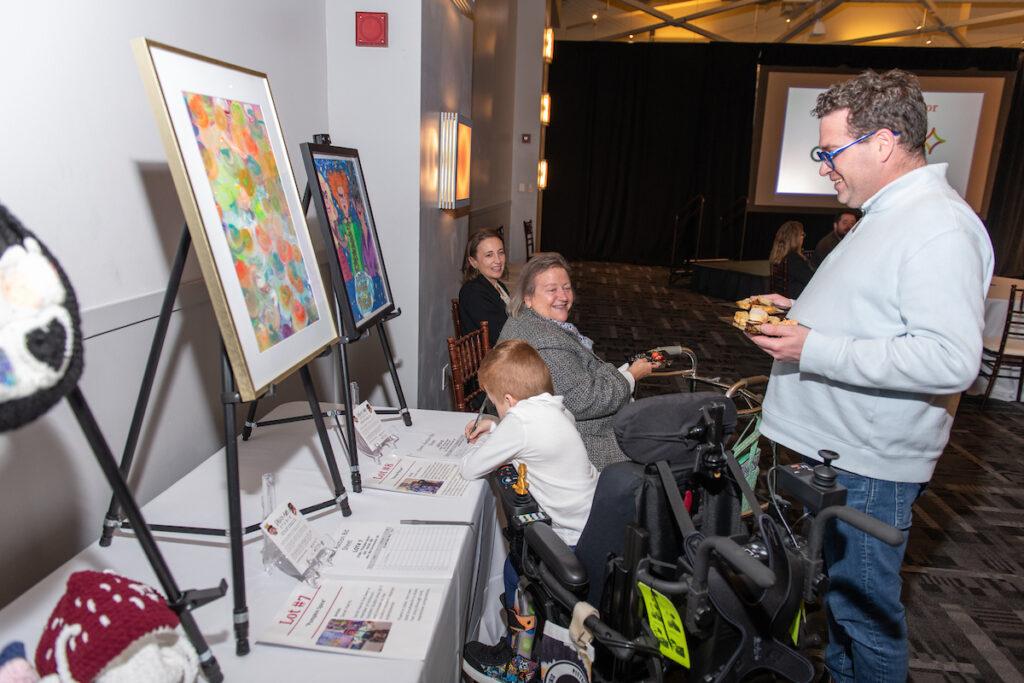 A young boy using a wheelchair bids on a silent auction item.