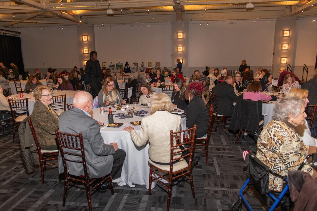 The ballroom with everyone seated at the table, waiting for the program to begin.