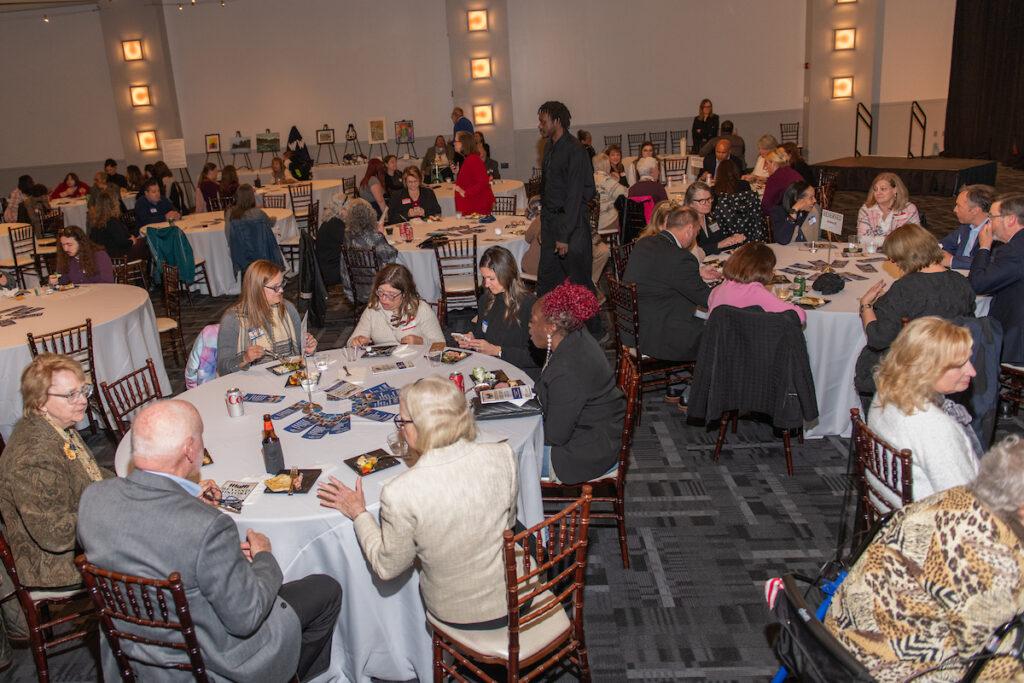 Guests seated at round tables in the filled ballroom.