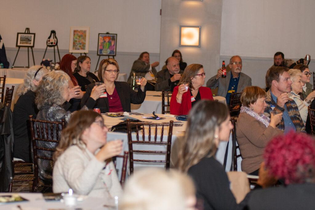 Guests seated at tables, raising their glasses for the toast.
