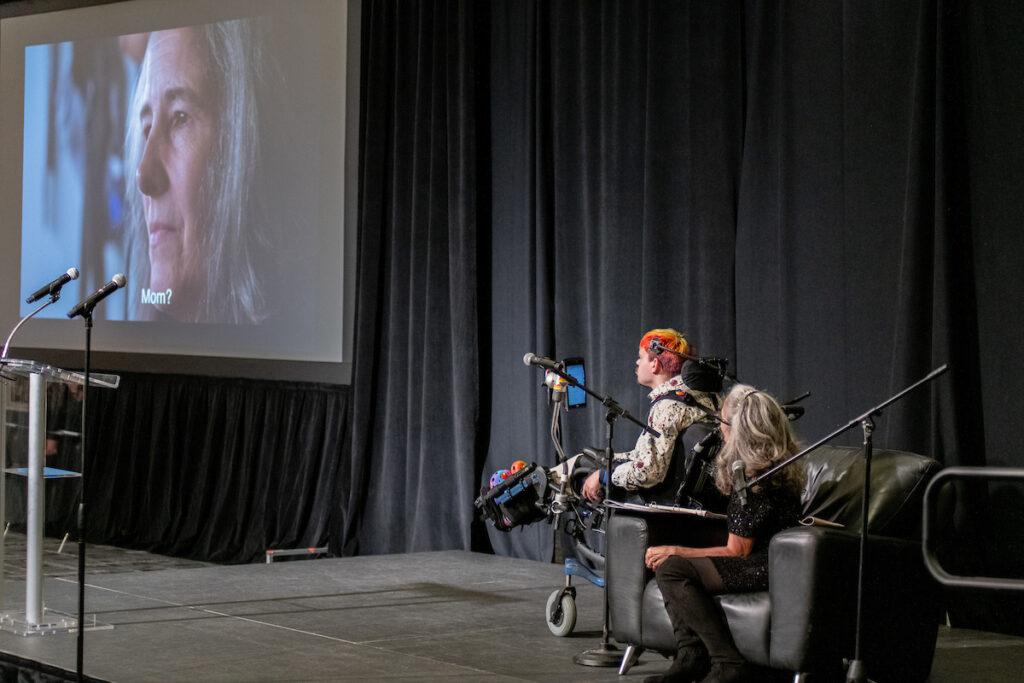 Ann Talman and Mark Steidl on stage watching the Woodys Order short film along with the rest of the audience.