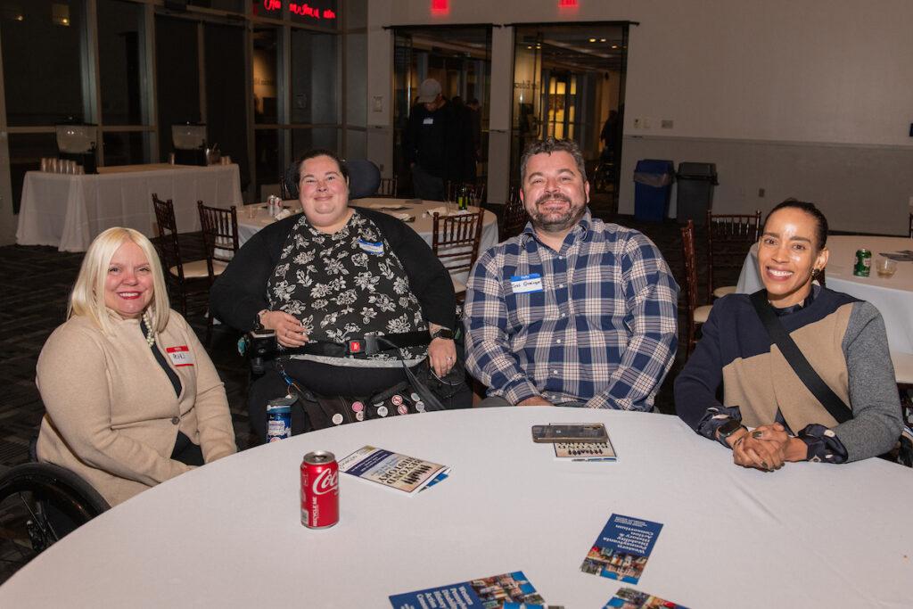 A group of guests seated at a table, posing for a photo - three women and one man.