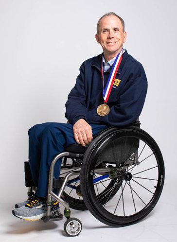 Rory Cooper, sitting his his wheelchair. He is smiling. He had his paralympic gold medal around his neck.